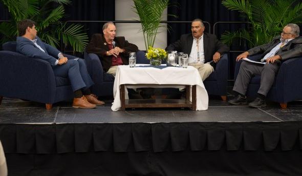 Four men sitting together on stage